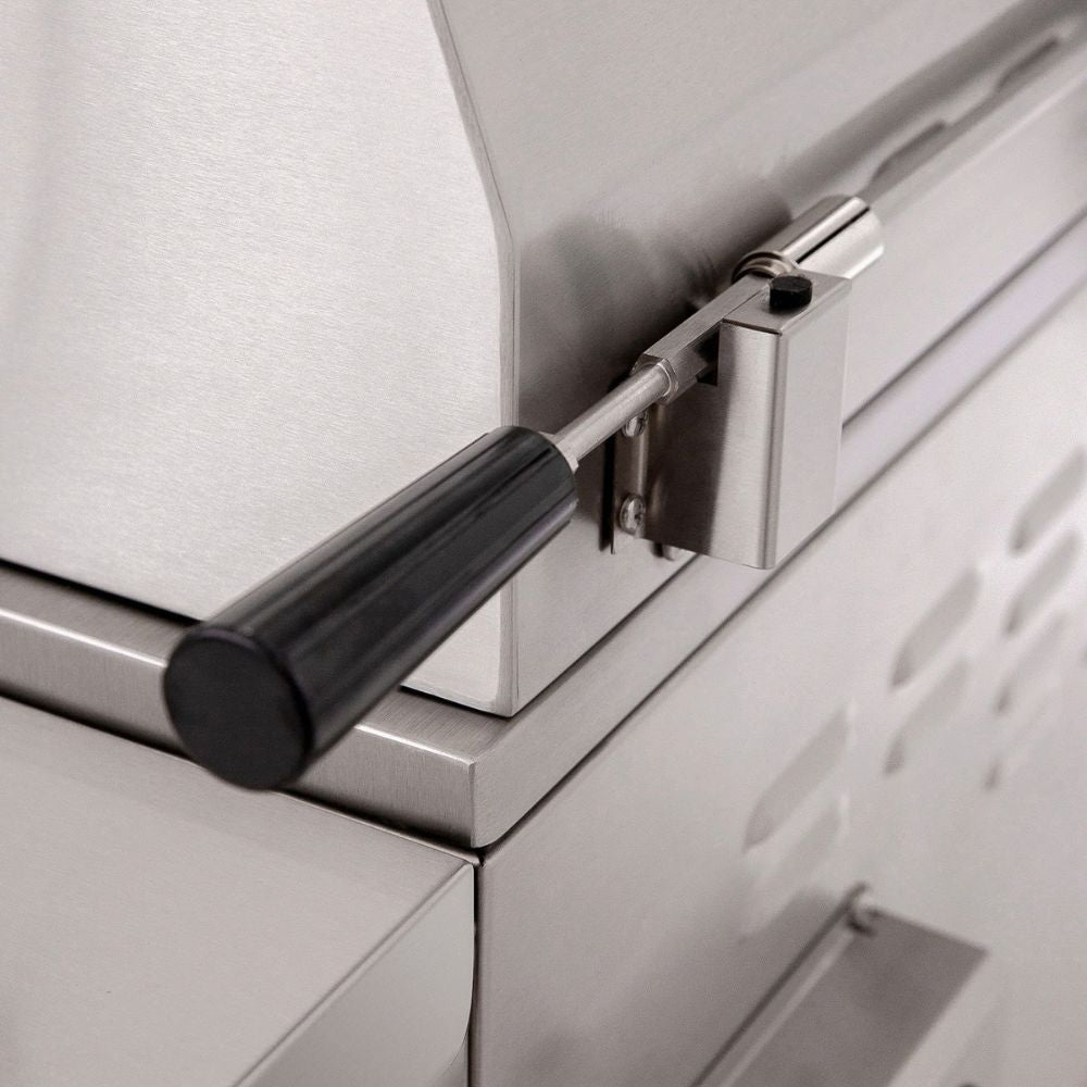 Close-up of a stainless steel outdoor grill or smoker with a black-handled latch mechanism.