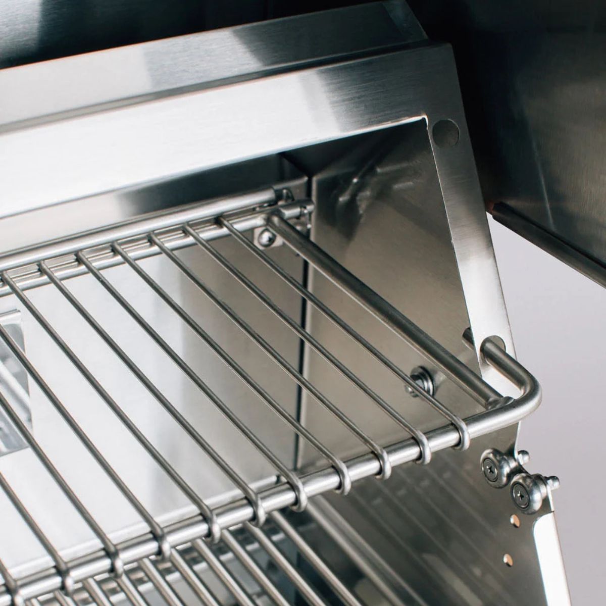 Close-up of a stainless steel wire shelf mounted inside a matching stainless steel appliance or enclosure.