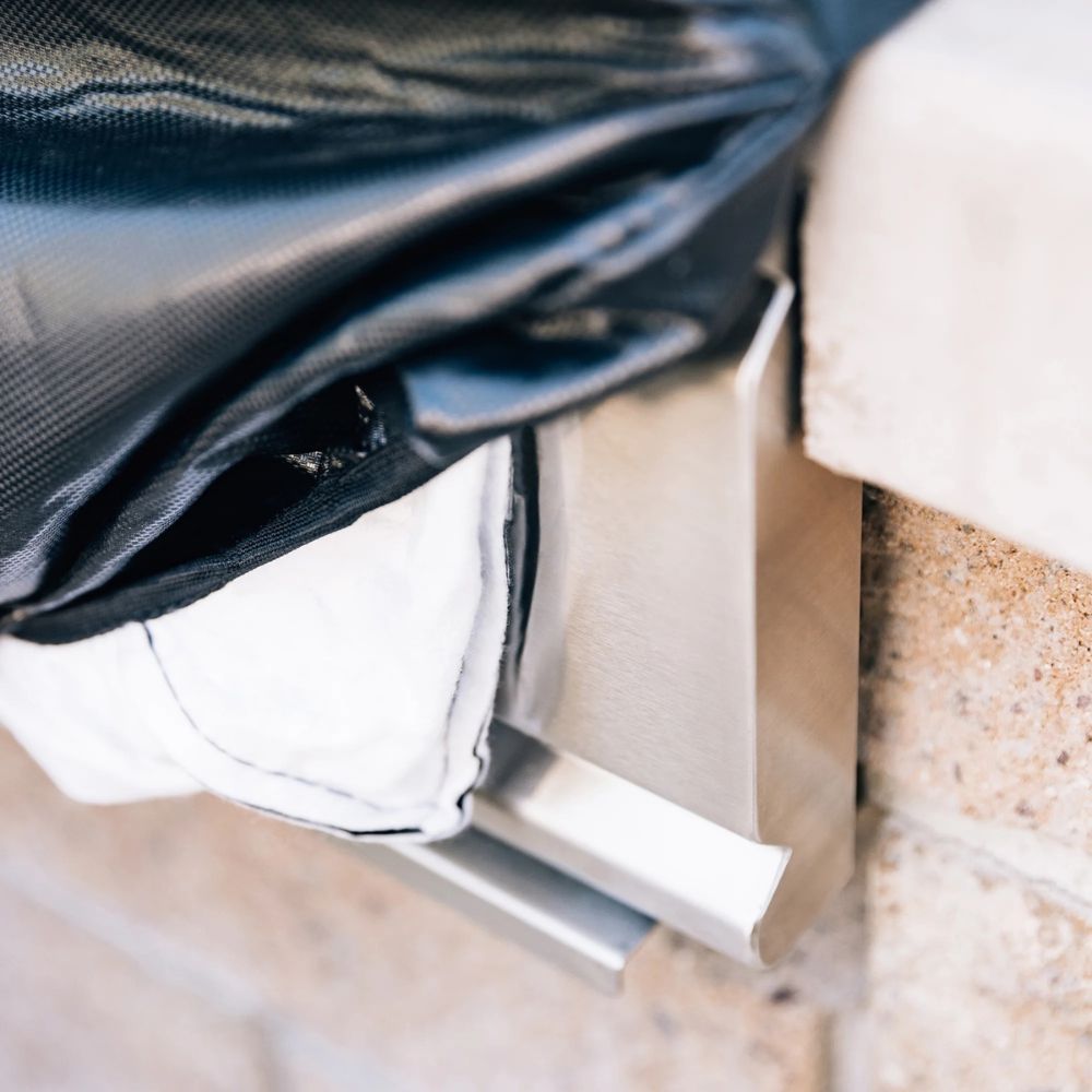 Close-up of a metal bracket attached to a concrete wall with a black and white fabric draped over it.