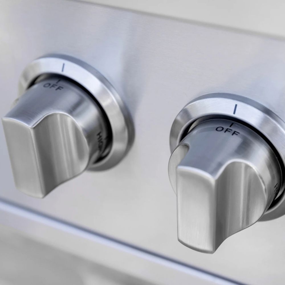 Close-up of two brushed stainless steel control knobs on a matching metal appliance surface, with the word OFF visible on each knob.