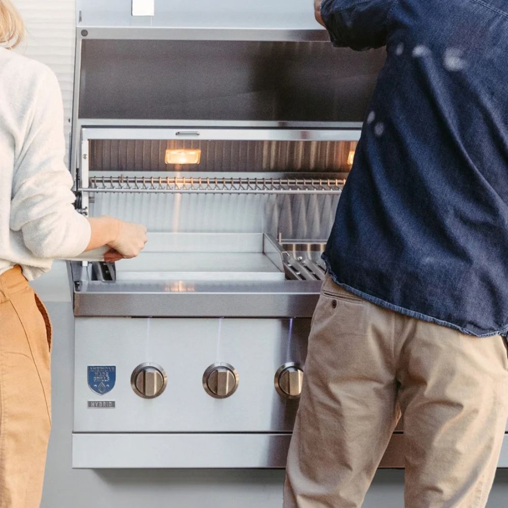 Two people interacting with a stainless steel grill in an indoor setting