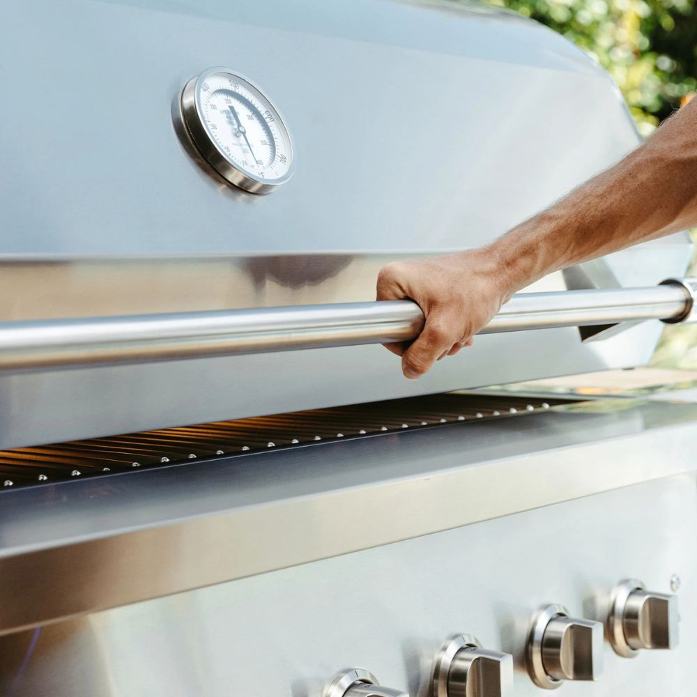 Hand opening a barbecue grill lid