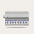 A stainless steel outdoor gas grill with a closed lid, featuring eight control knobs illuminated by blue LED lights on the front panel, set against a solid off-white background.
