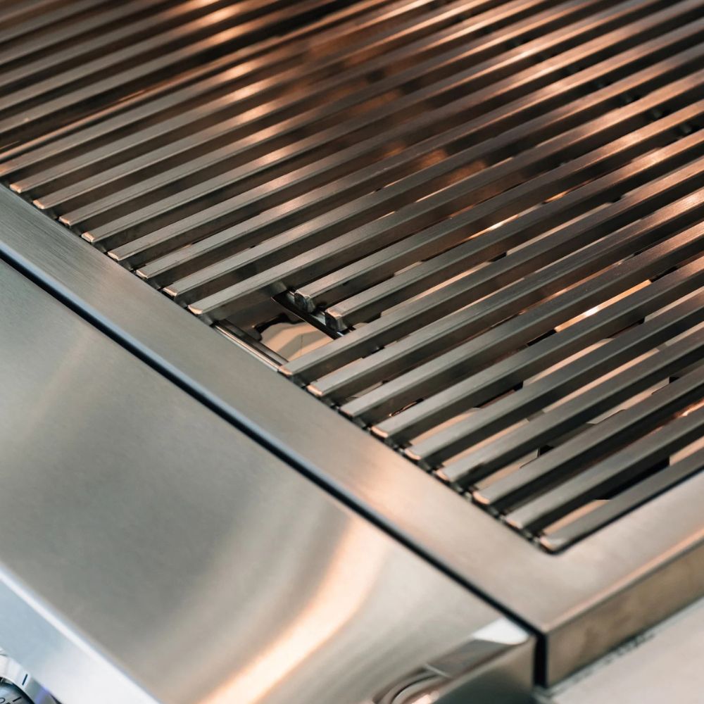Close-up of a stainless steel outdoor grill showing the slatted cooking grate and brushed metal body.