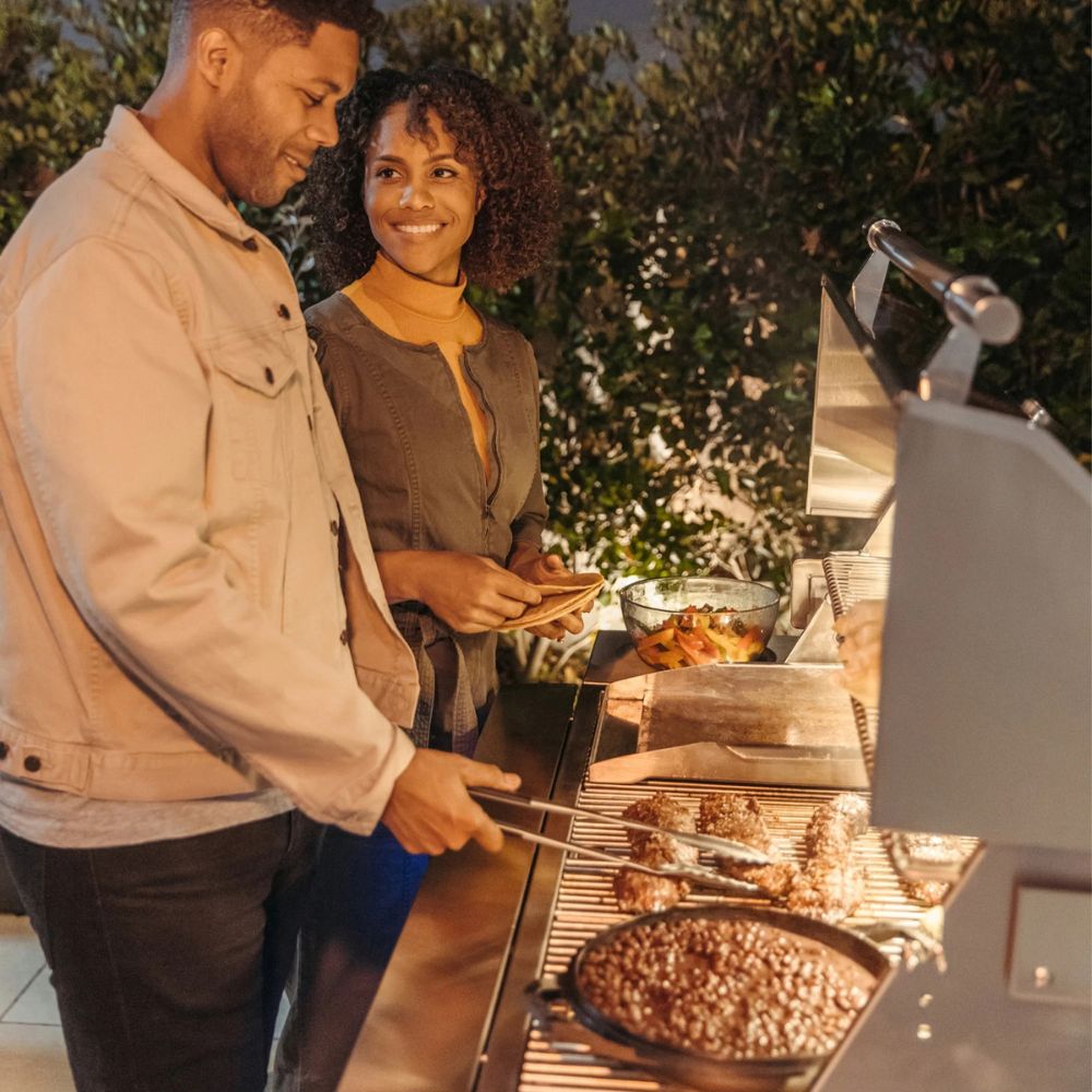 Man and woman grilling outdoors with food on a barbecue
