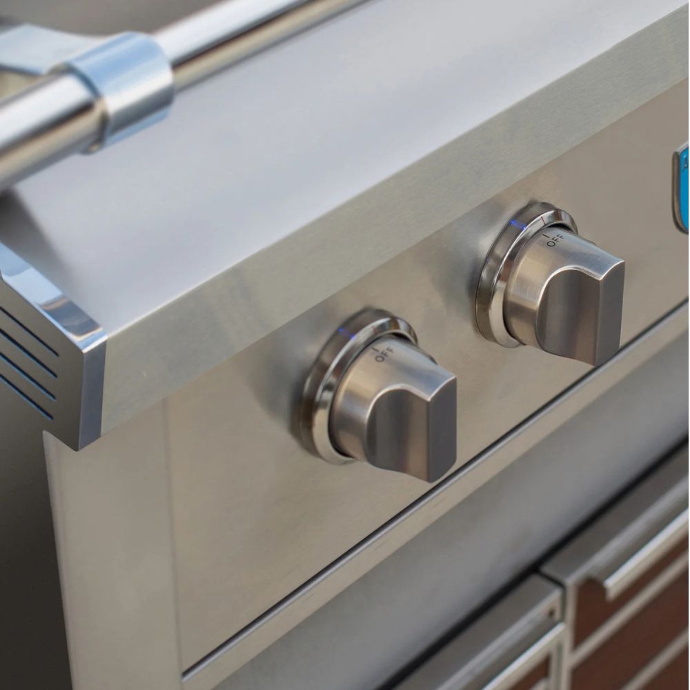 Close-up of stainless steel outdoor grill controls with two silver knobs on a brushed metal surface.