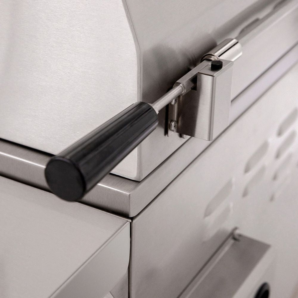Close-up of a stainless steel outdoor grill or smoker showing the lid latch mechanism with a black handle.