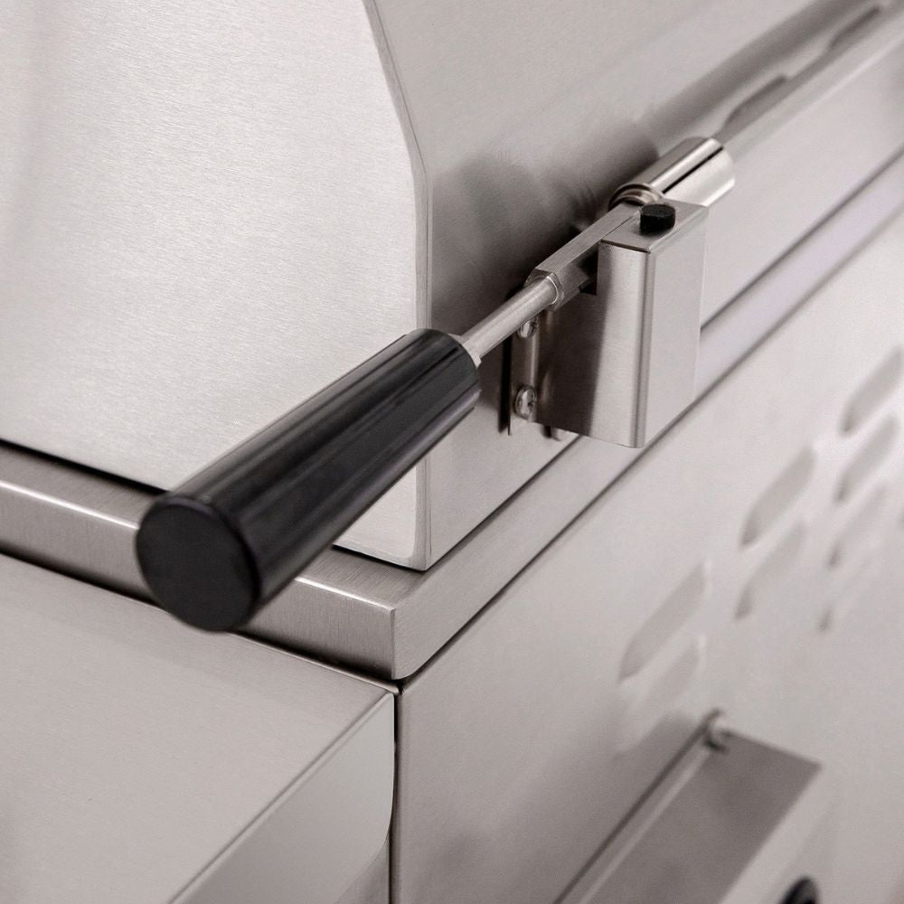 Close-up of a stainless steel outdoor grill or smoker with a black handle and metal latch mechanism.