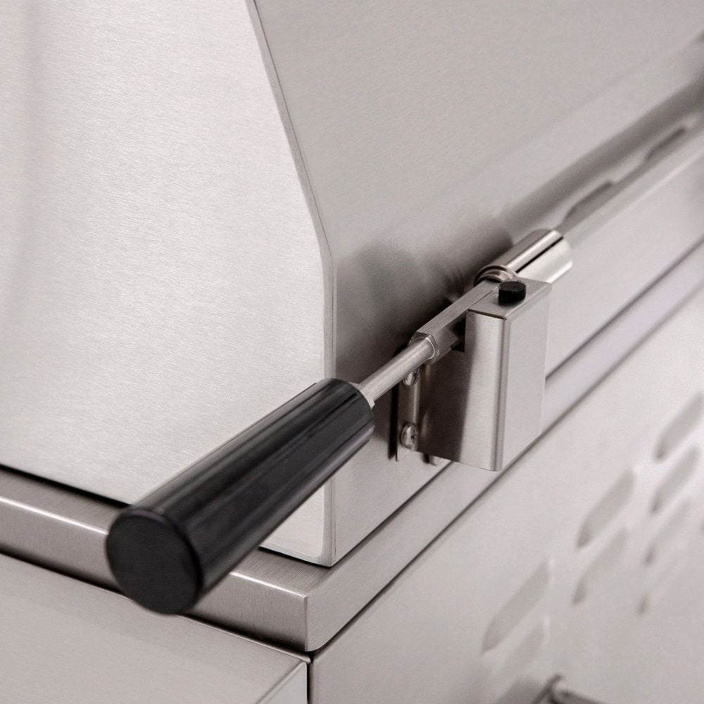 Close-up of a stainless steel outdoor grill or smoker showing the hinge, latch mechanism, and black handle.