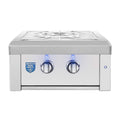 A stainless steel outdoor gas grill with two control knobs, blue indicator lights, a white grate on top, and an American Made Plus badge on the front, shown against a plain white background.