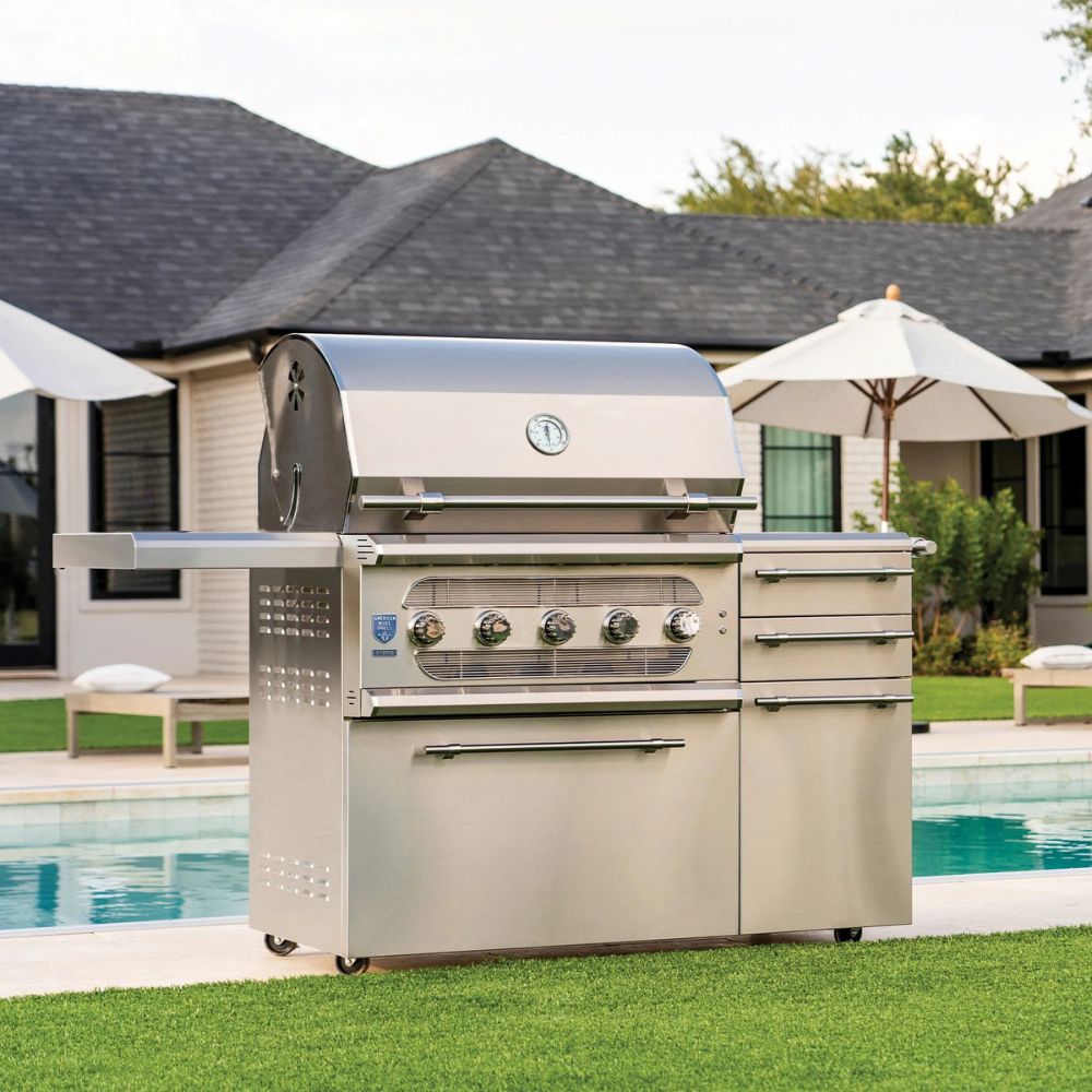 Stainless steel grill in a backyard setting with a pool and house in the background