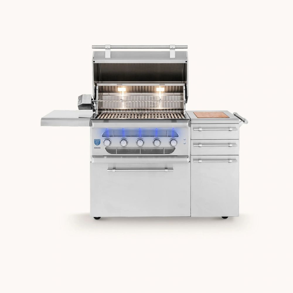 A stainless steel outdoor gas grill with an open lid, side deck shelf, three drawers, and a wood-look side panel, shown on a plain light background.