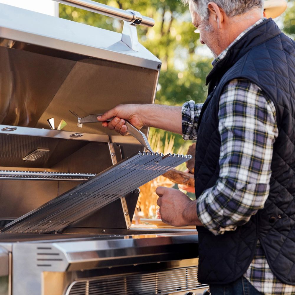 Man cleaning a grill with a brush outdoors