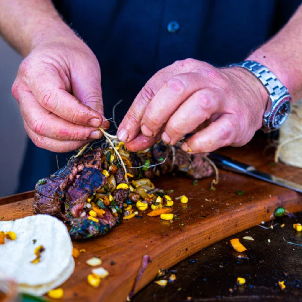 Person preparing a dish with a wooden board and ingredients