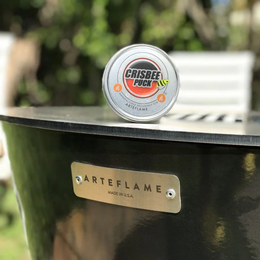 Crisbee Puck on top of an Arteflame barbecue grill with a blurred green background
