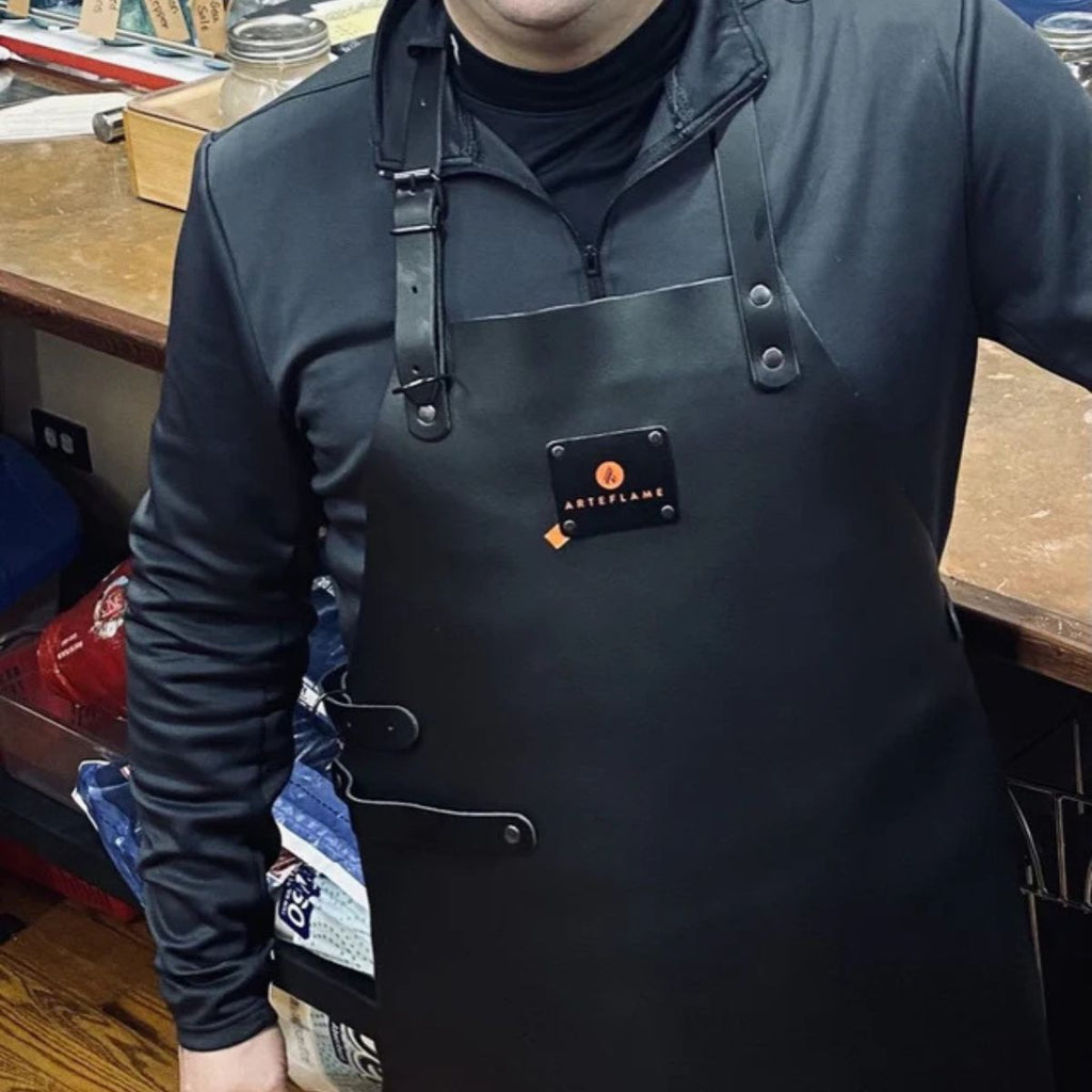 Person wearing a black apron with a brand logo in a workshop setting