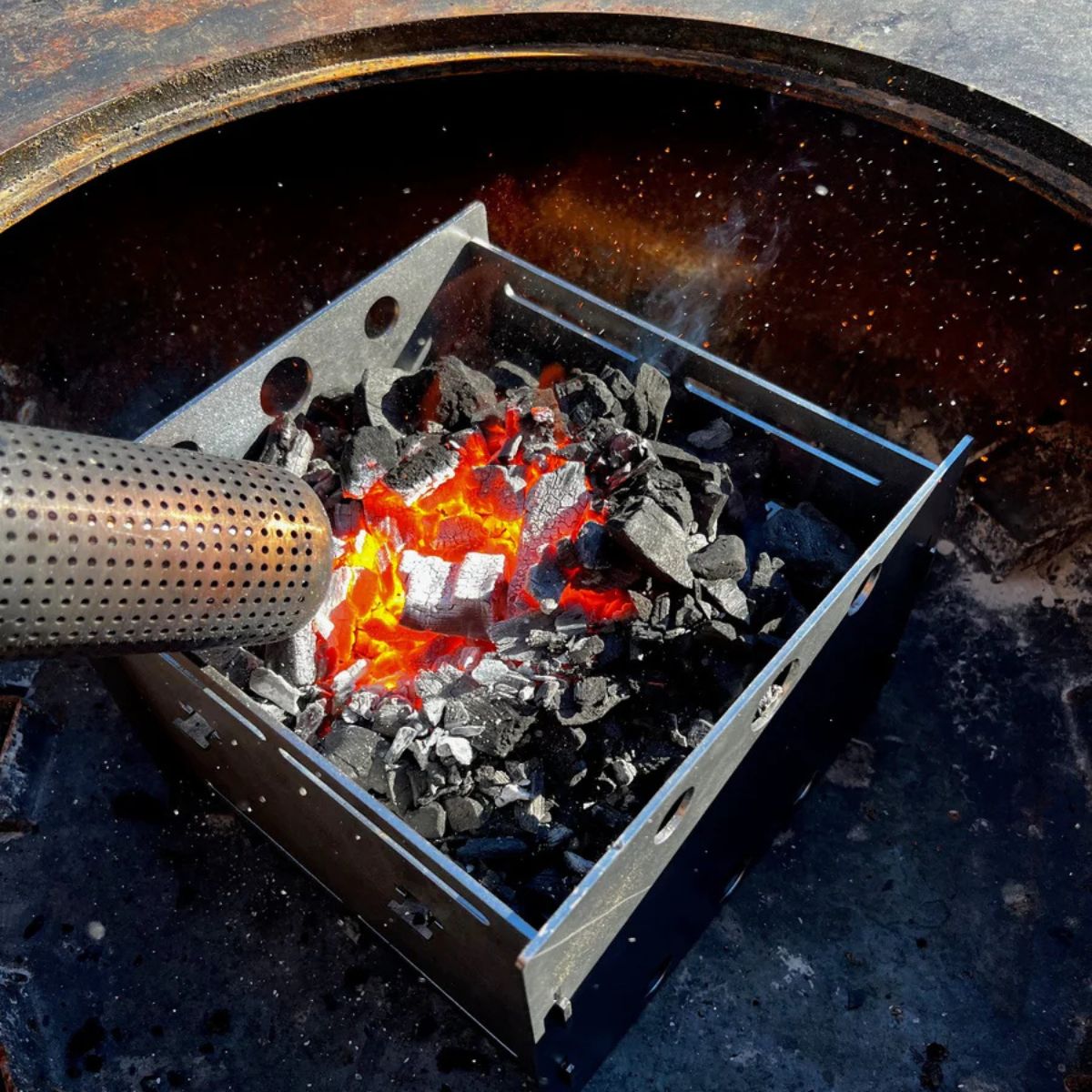 Metal fire starter box with flames inside a grill