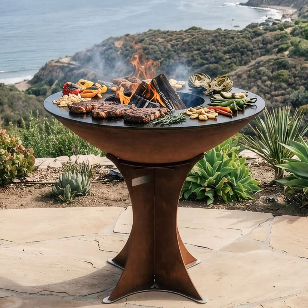 Outdoor grill with food on a patio overlooking a scenic landscape.